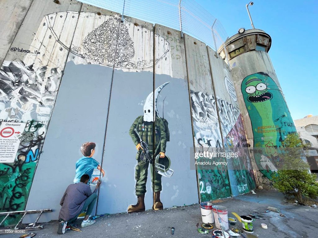 BETHLEHEM, WEST BANK - MAY 30: Palestinian artist Taqi Spateen paints the violations of Israeli soldiers against Palestinian children on discrimination wall in Bethlehem, West Bank on May 30, 2021. (Photo by Hisham K. K. Abu Shaqra/Anadolu Agency via Getty Images)